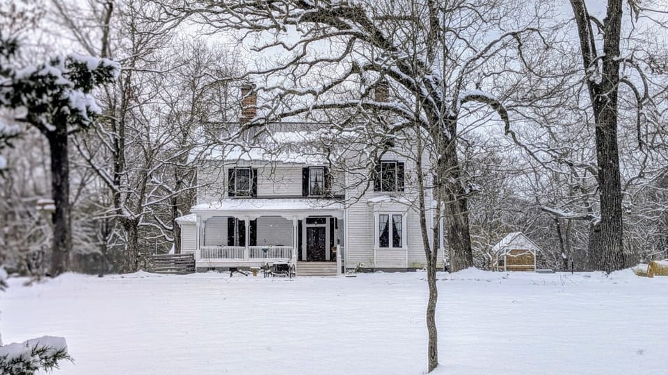 Historic farmhouse and immediate surroundings covered in a thick blanket of snow.